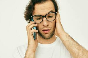 Beau homme dans une blanc T-shirt la communication par téléphone isolé Contexte photo