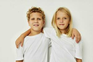 peu garçon et fille dans blanc t-shirts sont permanent suivant à mode de vie inchangé photo