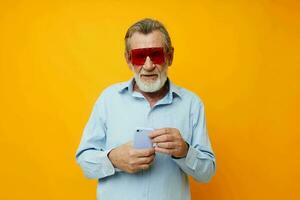personnes âgées homme dans à la mode rouge des lunettes avec une téléphone Jaune Contexte photo
