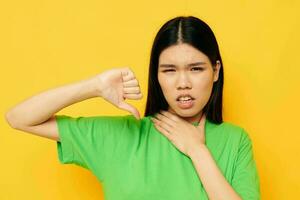 charmant Jeune asiatique femme dans vert t-shirts gestes avec le sien mains émotions studio modèle inchangé photo