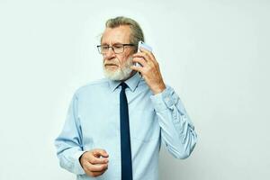 Sénior aux cheveux gris homme dans une chemise avec une attacher parlant sur le téléphone tondu vue photo