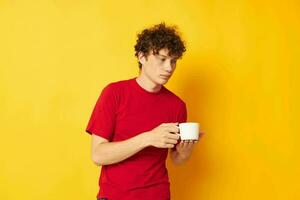 Jeune aux cheveux bouclés homme posant avec une blanc agresser et dans le mains de une boisson mode de vie inchangé photo