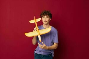 Jeune gars avec une jouet avion dans une violet T-shirt isolé Contexte inchangé photo