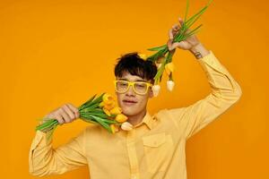 Beau gars donner fleurs porter lunettes Jaune chemise isolé Contexte inchangé photo