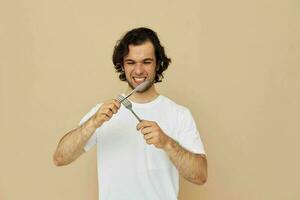 homme dans une blanc T-shirt avec couteau avec fourchette mode de vie inchangé photo