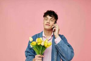 Jeune gars avec une bouquet de fleurs parlant sur le téléphone Date cadeau photo