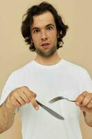 homme dans une blanc T-shirt avec couteau avec fourchette isolé Contexte photo