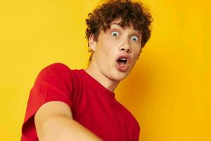 mignonne gars avec frisé cheveux dans une rouge T-shirt fermer photo