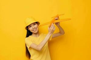 charmant Jeune asiatique femme de bonne humeur femme avec un avion dans le mains de amusement Jaune Contexte inchangé photo
