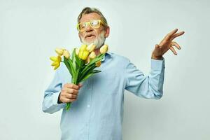 photo de retraité vieux homme dans une bleu chemise avec une bouquet de fleurs lumière Contexte