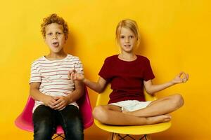 deux joyeux les enfants enfance séance sur chaises ensemble sur coloré Contexte photo