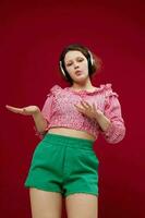 jolie femme dans rose chemisier et vert short avec écouteurs écoute à la musique photo