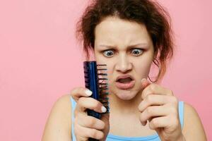 Jeune femme supprime cheveux sur une peigne insatisfaction isolé Contexte inchangé photo