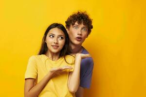 portrait de une homme et une femme dans coloré t-shirts posant relation amicale amusement Jaune Contexte inchangé photo