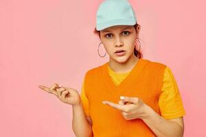 marrant fille dans un Orange chandail dans bleu casquettes main geste mode de vie inchangé photo