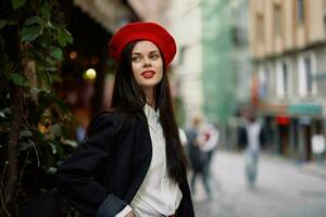 femme sourire mode modèle des promenades sur le rue dans le ville centre parmi le foule dans une veste et rouge béret et jeans, cinématique français mode style vêtements, Voyage à Istanbul photo