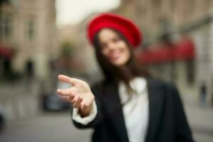 mode femme sourire avec les dents permanent sur le rue dans de face de le ville touristique suivre moi élégant vêtements avec rouge lèvres et rouge béret, voyage, cinématique couleur, rétro ancien style, Urbain mode. photo