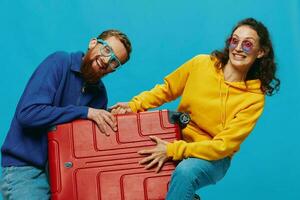 femme et homme sourire les valises dans main avec Jaune et rouge valise sourire amusant, sur bleu arrière-plan, emballage pour une voyage, famille vacances voyage. photo