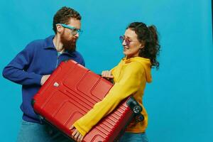 femme et homme sourire les valises dans main avec Jaune et rouge valise sourire amusant, sur bleu arrière-plan, emballage pour une voyage, famille vacances voyage. photo