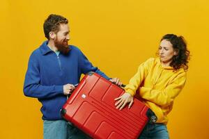 femme et homme souriant, les valises dans main avec Jaune et rouge valise souriant joyeusement et courbé, Jaune arrière-plan, Aller sur une voyage, famille vacances voyage, jeunes mariés. photo