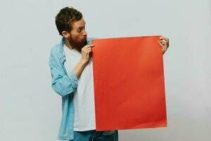 portrait de un adulte Masculin sur une gris Contexte avec une rouge pièce de papier pour votre conception et texte, mise en page, copie espace, espace pour texte photo