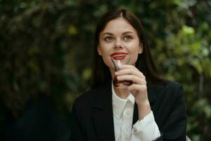 femme avec rouge lèvres sourire avec les dents en buvant thé dans une café de une turc verre agresser sur le rue, été voyage, vacances dans le ville photo