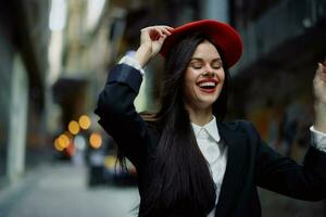 mode femme sourire avec les dents et amusement touristique dans élégant vêtements dans veste et rouge béret en marchant vers le bas étroit ville rue en volant cheveux, voyage, français style, cinématique couleur, rétro ancien style. photo