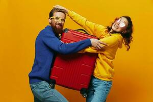 femme et homme souriant, les valises dans main avec Jaune et rouge valise souriant joyeusement et courbé, Jaune arrière-plan, Aller sur une voyage, famille vacances voyage, jeunes mariés. photo