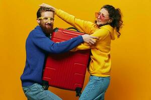 femme et homme souriant, les valises dans main avec Jaune et rouge valise souriant joyeusement et courbé, Jaune arrière-plan, Aller sur une voyage, famille vacances voyage, jeunes mariés. photo