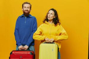 femme et homme souriant, les valises dans main avec Jaune et rouge valise souriant joyeusement et courbé, Jaune arrière-plan, Aller sur une voyage, famille vacances voyage, jeunes mariés. photo