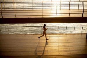 jeune femme prenant l'exercice de course par la promenade de la rivière photo