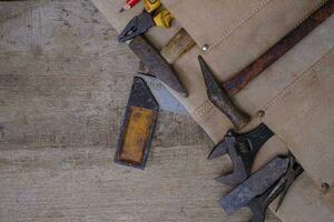 Collection d'outils à main vieux bois en tablier en cuir sur un établi en bois rugueux photo