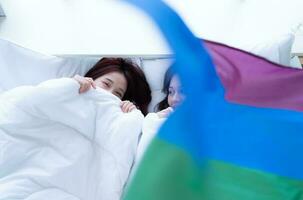 dans une Hôtel chambre à coucher, un lgbt couple blotti ensemble sur le lit Heureusement. photo