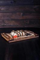 rouleaux de fruits de mer sur un plateau en bois, belle portion, fond sombre photo
