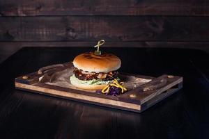 cheeseburger sur un plateau en bois dans un restaurant, sur fond sombre photo
