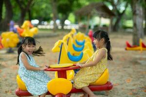 les enfants asseoir sur une carrousel dans le terrain de jeux ensemble. les enfants en jouant à Extérieur terrain de jeux dans le parc sur été vacances. en bonne santé activité. photo