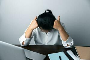 une affaires Bureau ouvrier est un asiatique femme est séance dans de face de le portable ordinateur. une femme d'affaires stressant sa corps partie des doigts, mains bras. une femmebureau directeur est épuisé à sa lieu de travail. photo