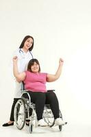 belle femme médecin guérit les maux des patientes obèses asiatiques assises sur un fauteuil roulant. l'obésité est un problème de santé pour le corps. concept de perdre du poids. espace de copie. fond blanc photo