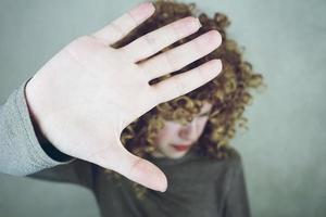 gros plan sur la paume de la main d'une belle et jeune femme qui couvre son visage ses cheveux sont bouclés et blonds elle a l'air en colère ou fatiguée photo