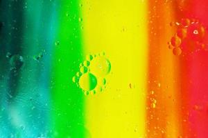 une belle macro colorée de bulles d'huile sur l'eau avec une texture à rayures jaune, rouge, verte, orange et bleue comme motif de fond