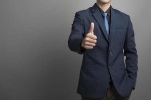 Close up of businessman in blue suit Thumbs up sur fond gris photo