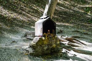 orthodoxe bougies dans le forêt en dessous de une arbre dans une boîte. le prière pierre par le route photo