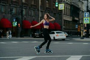 photo en plein air d'une femme sim qui roule sur des patins à roues alignées entraîne différents groupes musculaires des jambes et du tronc développe l'endurance gère son poids brûle des calories améliore l'équilibre. entraînement cardio