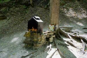 orthodoxe bougies dans le forêt en dessous de une arbre dans une boîte. le prière pierre par le route photo