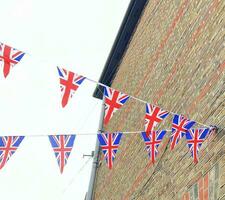 Britanique syndicat jack drapeaux pendaison à le rue contre brique mur, prêt à nationale vacances fête. rue fête décorations dans le Royaume-Uni ville. photo