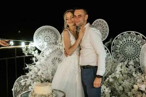 les jeunes mariés coupent et goûtent joyeusement le gâteau de mariage photo