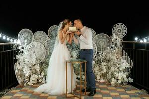 les jeunes mariés coupent et goûtent joyeusement le gâteau de mariage photo