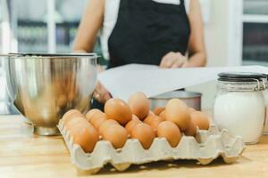 poulet Oeuf avec Ingrédients pour cuisson sur table avec femme boulanger dans Contexte. photo