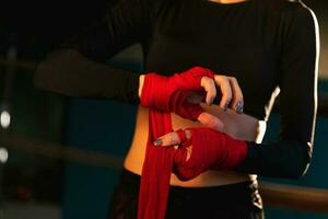 femmes soi la défense fille pouvoir. femme combattant en train de préparer pour bats toi emballage mains avec rouge boxe enveloppements des sports protecteur des pansements, fort mains prêt pour bats toi actif exercice sparring faire des exercices formation photo