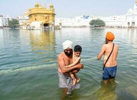 Amritsar, Inde - février 26 2023 - non identifié dévots prise saint tremper dans sarovar à d'or temple - harmandir sahib dans Amritsar, Pendjab, Inde, célèbre Indien sikh repère, d'or temple photo